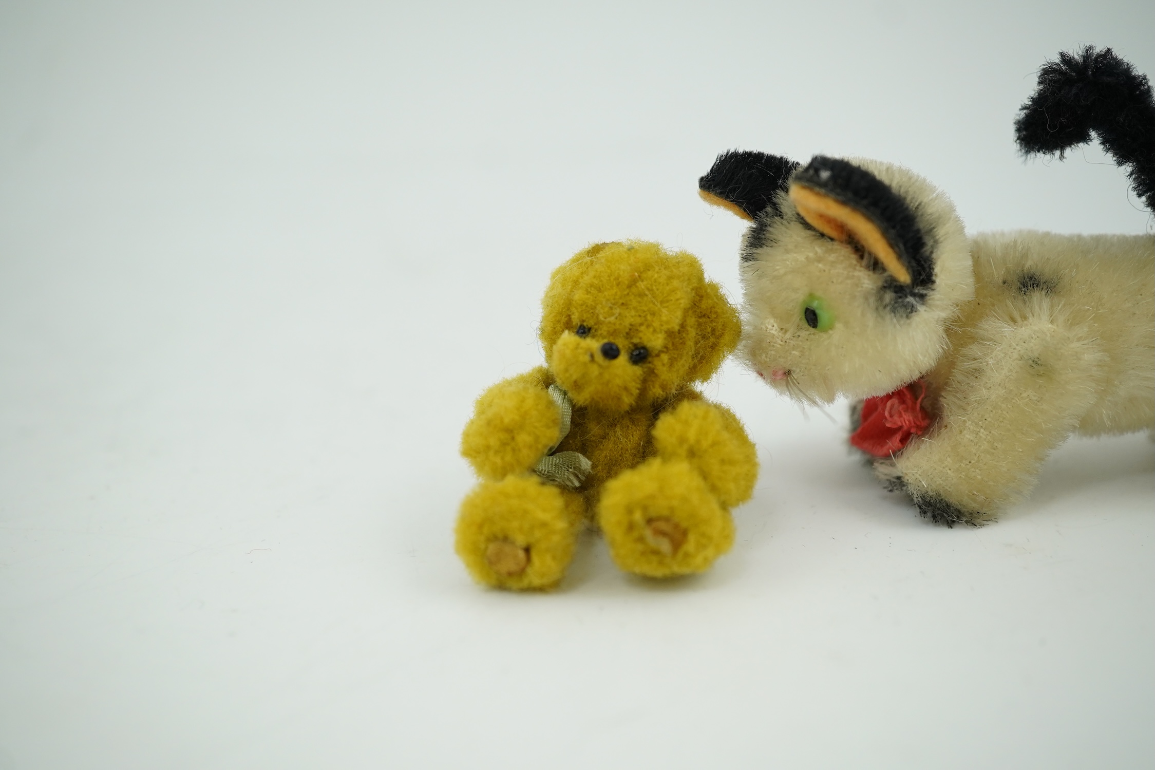 A small Schuco cat with revolving head and a tiny jointed teddy bear, largest 9cm in length. Condition - fair to good